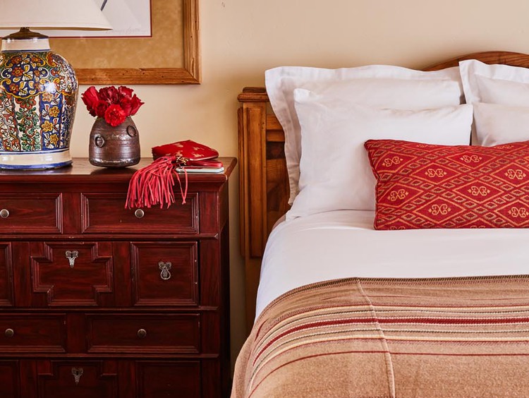 Red pillow and white sheets beside side table